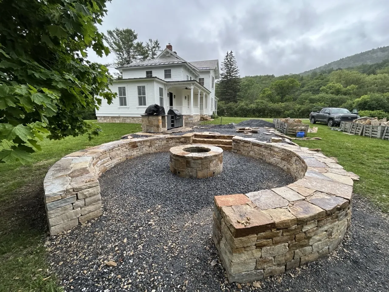 Curved natural-stone wall and fire feature in a landscaped yard